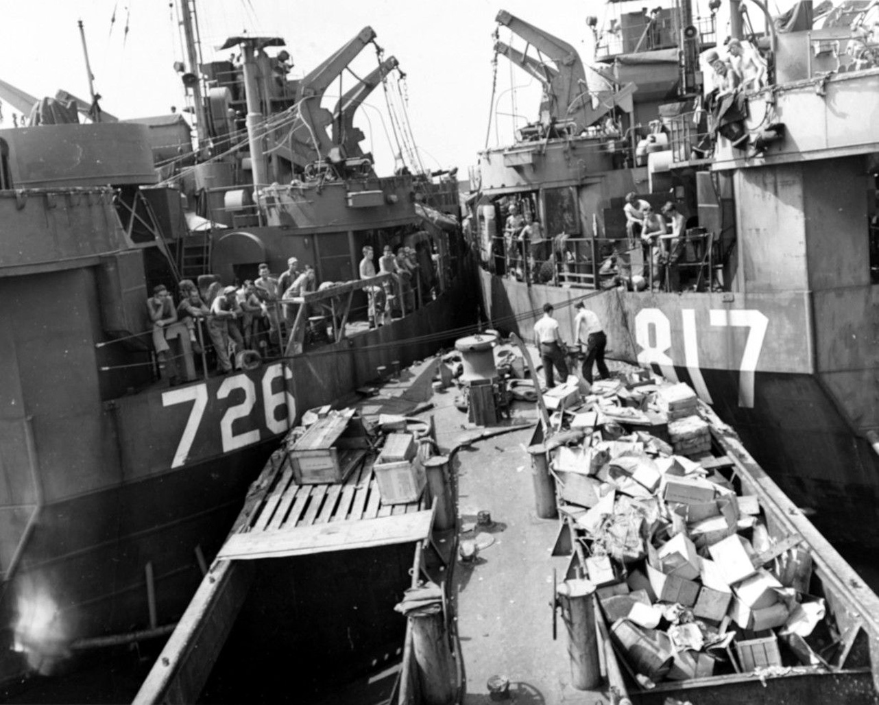 LST-726 on the left and LST-817 on the right, with their hull numbers visible, transferring rubbish into the lighter YG-33 between them at Guam